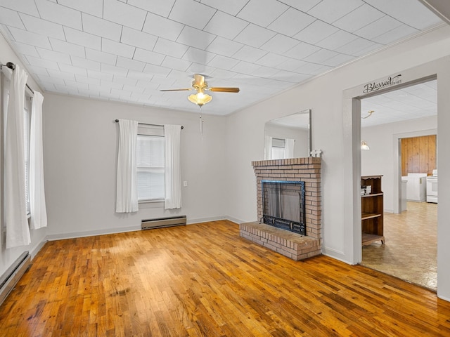 unfurnished living room featuring baseboard heating, a fireplace, and hardwood / wood-style flooring