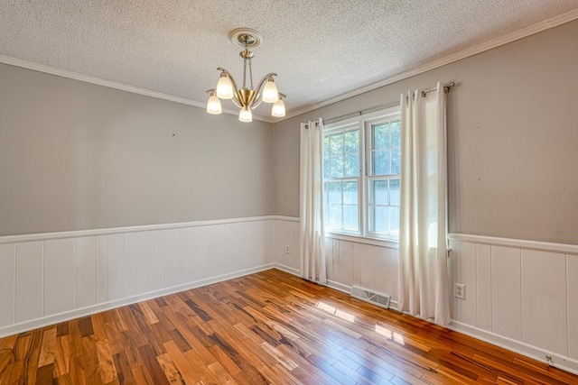 unfurnished room featuring a notable chandelier, a textured ceiling, hardwood / wood-style flooring, and crown molding