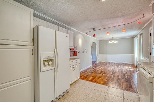 kitchen with ornamental molding, a textured ceiling, white fridge with ice dispenser, stainless steel dishwasher, and light hardwood / wood-style flooring