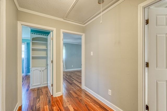 corridor with wood-type flooring, a textured ceiling, and crown molding