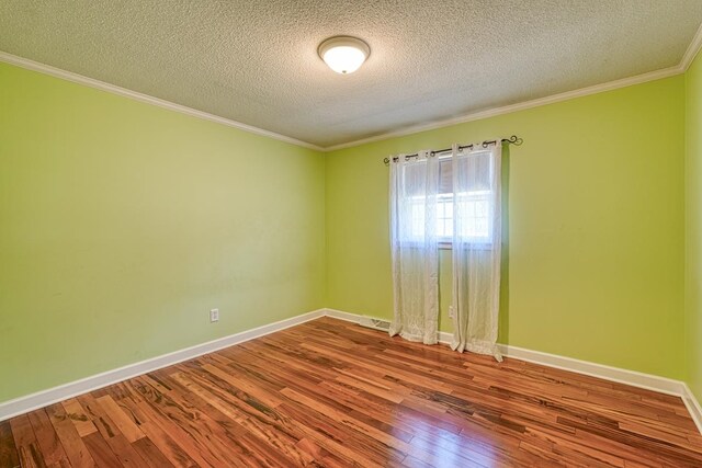 empty room with hardwood / wood-style flooring, a textured ceiling, and ornamental molding