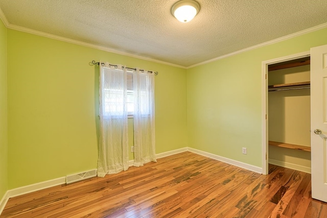 unfurnished bedroom with hardwood / wood-style floors, a textured ceiling, a closet, and ornamental molding