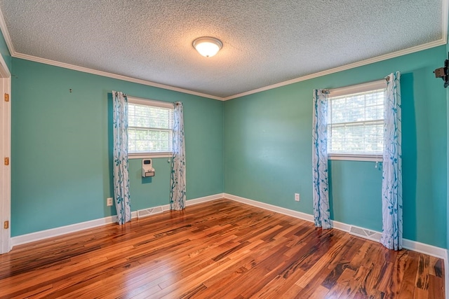 empty room with hardwood / wood-style floors, crown molding, and a textured ceiling