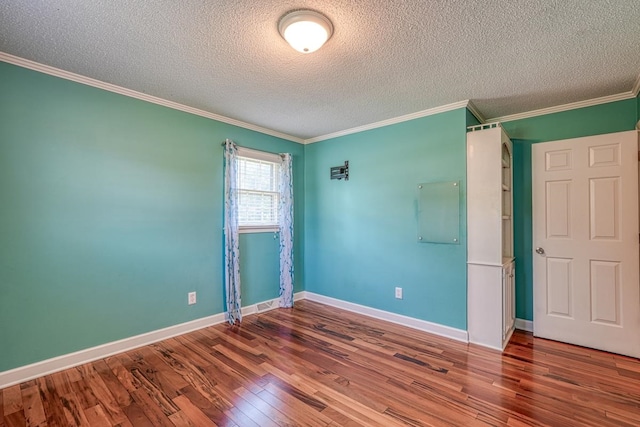 spare room featuring wood-type flooring, a textured ceiling, and crown molding