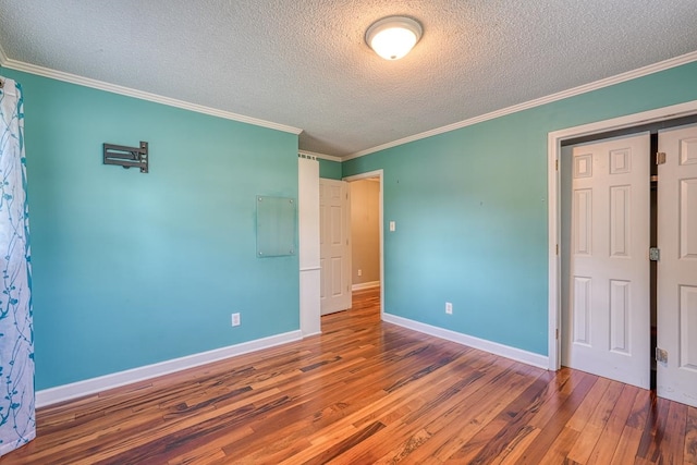 unfurnished bedroom featuring ornamental molding, hardwood / wood-style flooring, and a closet