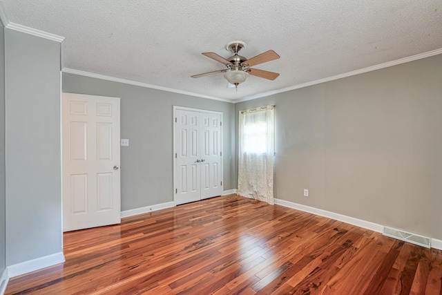 unfurnished bedroom featuring hardwood / wood-style flooring, ceiling fan, a textured ceiling, and crown molding