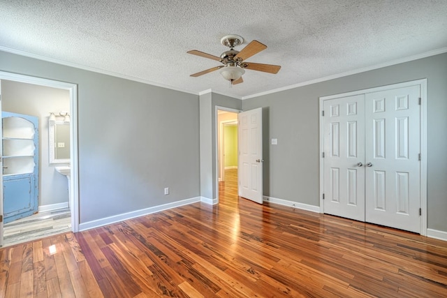 unfurnished bedroom featuring ceiling fan, a textured ceiling, crown molding, a closet, and dark hardwood / wood-style flooring