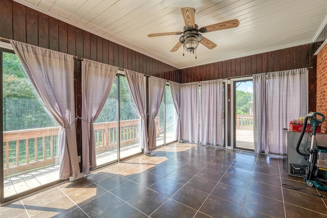 interior space featuring wooden walls, ceiling fan, and plenty of natural light