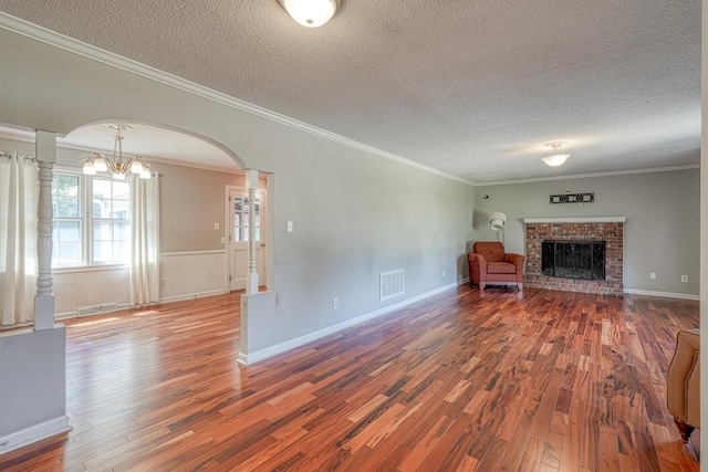 9 Brookdale Acres, Lyman, SC 29365 - unfurnished living room featuring a textured ceiling, wood finished floors, a fireplace, ornamental molding, and arched walkways
