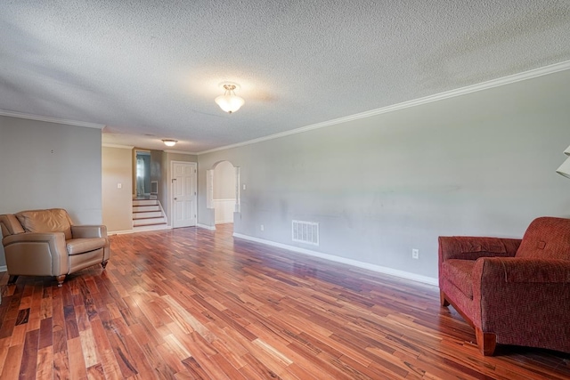 living area featuring a textured ceiling, ornamental molding, and hardwood / wood-style flooring