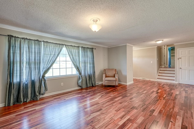 unfurnished room featuring hardwood / wood-style flooring, a textured ceiling, and ornamental molding