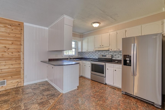 kitchen with tasteful backsplash, stainless steel appliances, wood walls, white cabinets, and kitchen peninsula