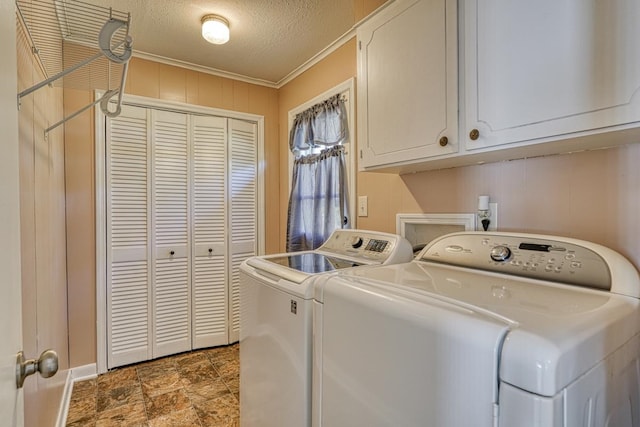 laundry area with cabinets, wood walls, ornamental molding, a textured ceiling, and washer and clothes dryer