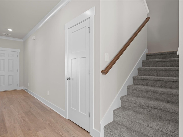 stairs featuring ornamental molding and hardwood / wood-style floors