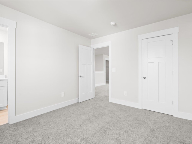 unfurnished bedroom with connected bathroom and light carpet