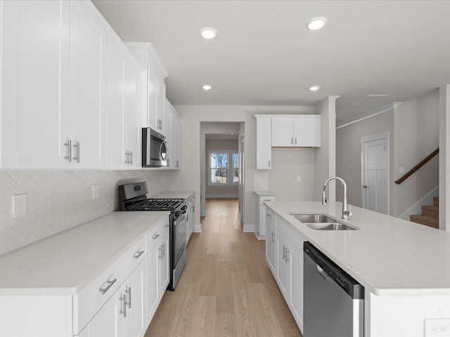 kitchen with sink, tasteful backsplash, stainless steel appliances, a kitchen island with sink, and white cabinets