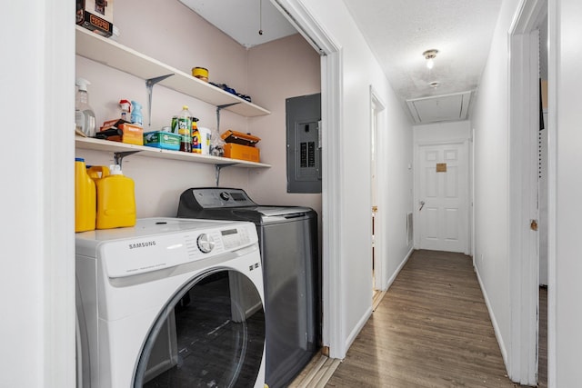 laundry room featuring a textured ceiling, washing machine and dryer, electric panel, and hardwood / wood-style floors