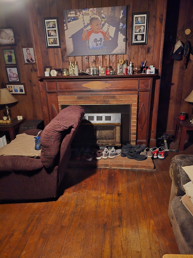 living room with wood walls, wood-type flooring, and a fireplace