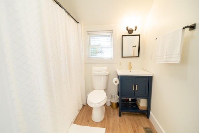 bathroom with toilet, vanity, and wood-type flooring