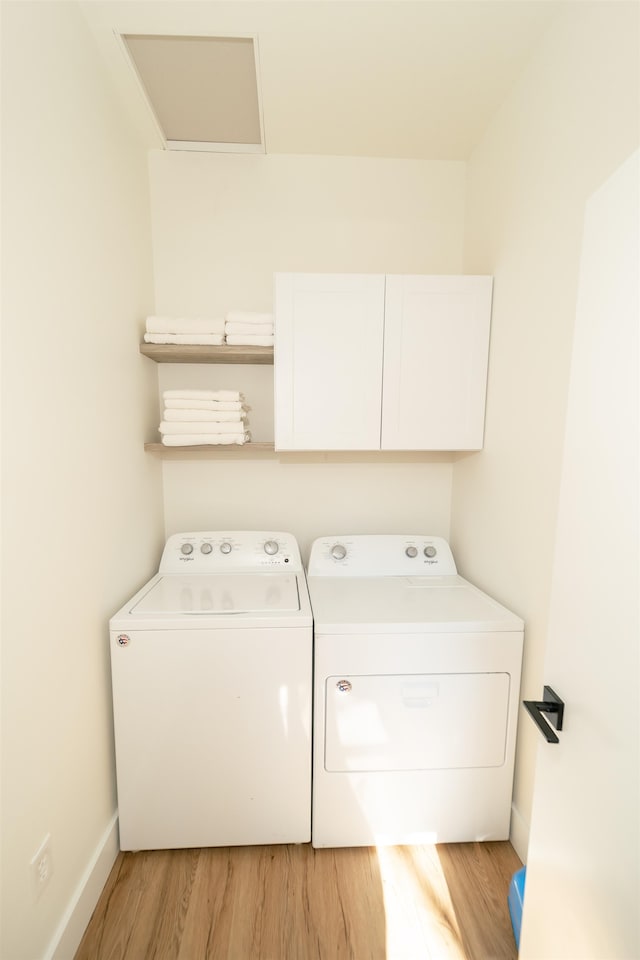 laundry room with washing machine and dryer, cabinets, and light hardwood / wood-style floors