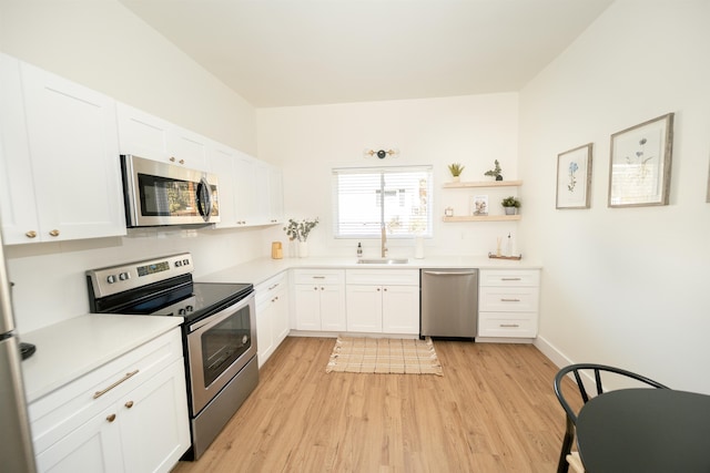 kitchen with stainless steel appliances, light hardwood / wood-style floors, white cabinets, and sink