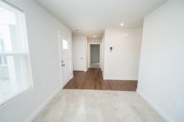 hallway with a wealth of natural light and light colored carpet