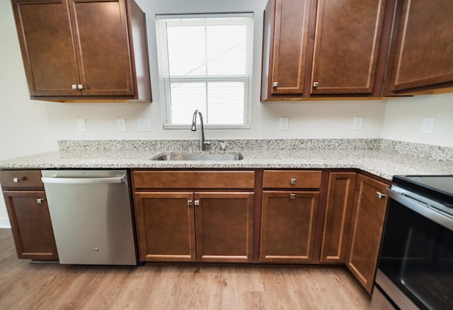 kitchen with light stone counters, sink, light wood-type flooring, and appliances with stainless steel finishes