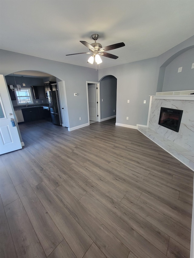 unfurnished living room featuring a fireplace, wood-type flooring, and ceiling fan