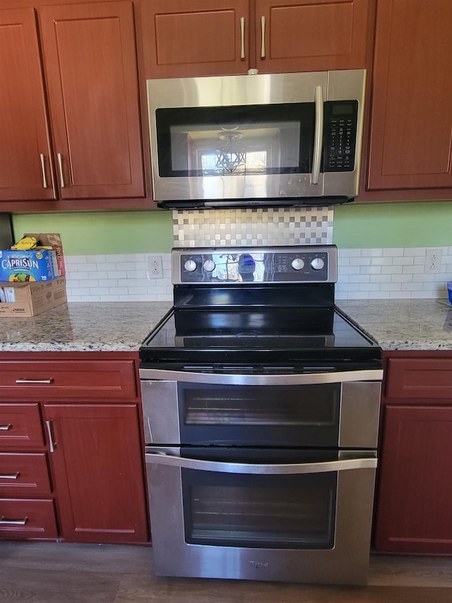 kitchen with light stone countertops, backsplash, and appliances with stainless steel finishes