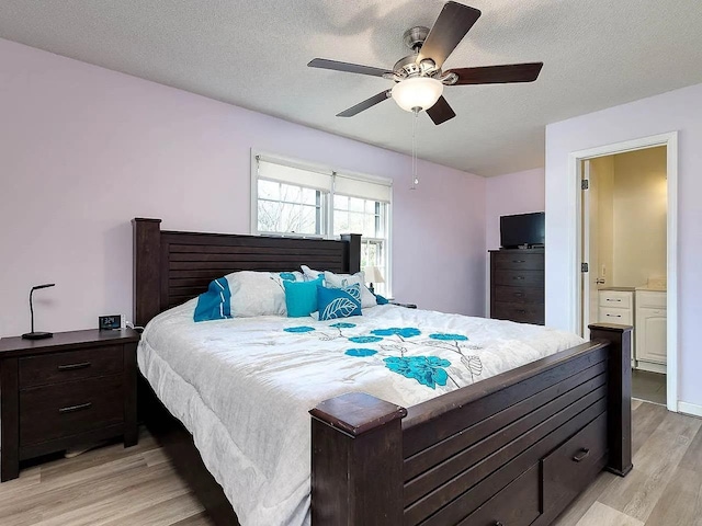 bedroom with ensuite bath, a textured ceiling, ceiling fan, and light hardwood / wood-style flooring