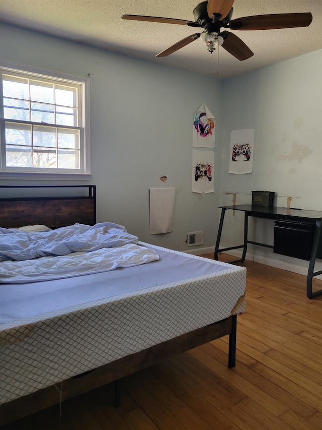 bedroom with ceiling fan, a textured ceiling, and wood-type flooring