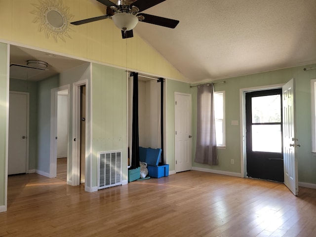 foyer with a textured ceiling, light wood-type flooring, lofted ceiling, and ceiling fan