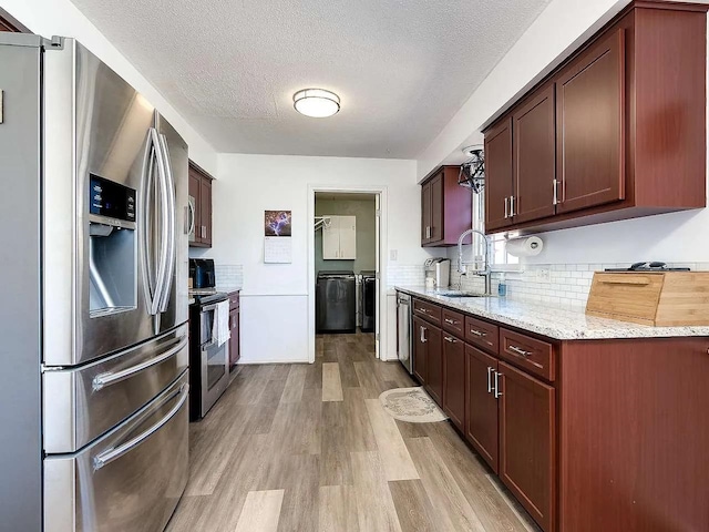 kitchen featuring stainless steel appliances, light hardwood / wood-style floors, sink, light stone countertops, and a textured ceiling