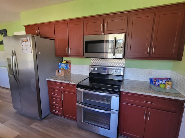 kitchen with dark wood-type flooring, tasteful backsplash, appliances with stainless steel finishes, and light stone counters