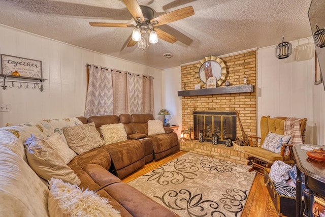 living room with hardwood / wood-style floors, a brick fireplace, wooden walls, and a textured ceiling