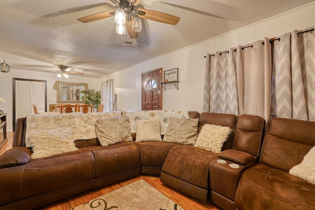 living room with hardwood / wood-style floors, ceiling fan, and a textured ceiling