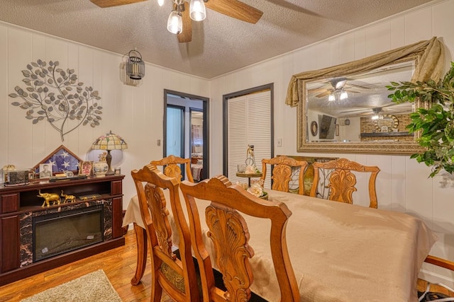 dining room with ceiling fan, crown molding, light hardwood / wood-style floors, and a textured ceiling