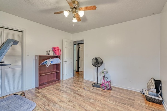 miscellaneous room with light hardwood / wood-style flooring, ceiling fan, and a textured ceiling