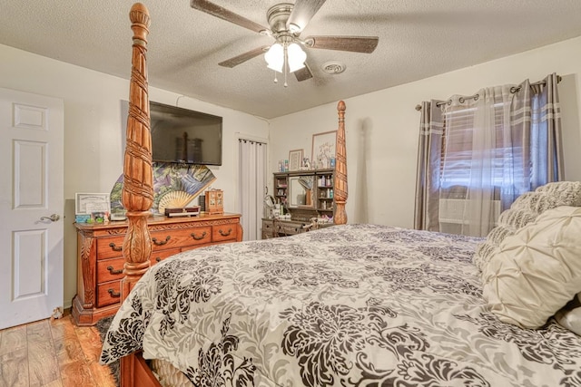 bedroom featuring ceiling fan, light wood-type flooring, and a textured ceiling