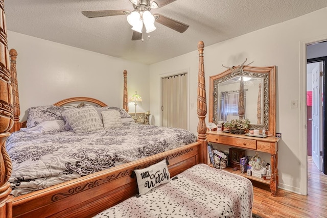 bedroom featuring light hardwood / wood-style flooring, ceiling fan, and a textured ceiling