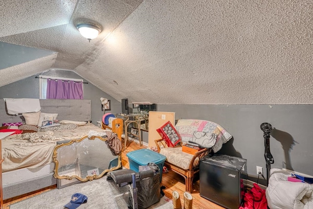 bedroom featuring a textured ceiling, wood-type flooring, and vaulted ceiling