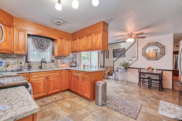 kitchen featuring kitchen peninsula, sink, a healthy amount of sunlight, and a textured ceiling