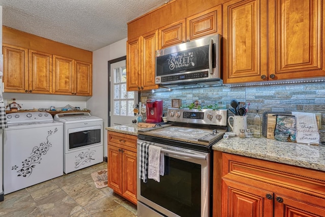 kitchen with light stone countertops, appliances with stainless steel finishes, a textured ceiling, and washer and clothes dryer