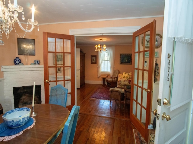 dining space with hardwood / wood-style floors, a brick fireplace, french doors, and ornamental molding