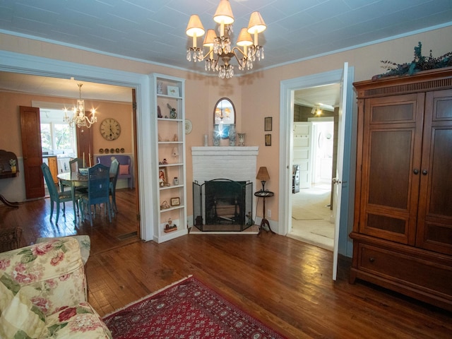 living room featuring a chandelier, dark hardwood / wood-style floors, a brick fireplace, and ornamental molding