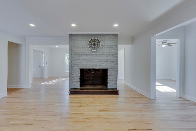 unfurnished living room featuring crown molding, ceiling fan, a fireplace, and light hardwood / wood-style floors