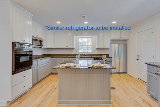 kitchen with sink, a center island, light hardwood / wood-style flooring, crown molding, and black appliances