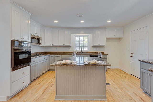 kitchen with sink, a center island, light hardwood / wood-style floors, and black appliances