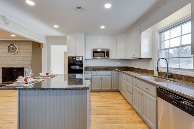 kitchen with light hardwood / wood-style floors, ornamental molding, sink, and appliances with stainless steel finishes