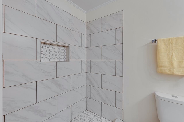 bathroom with tiled shower, toilet, and crown molding